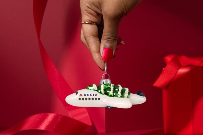 Soar into style with our Festive Delta Plane Ornament. Made of glass with a whimsical tree on top, make sure to snag one before it takes off!&nbsp;