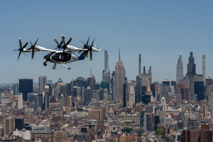 Joby electric air taxi flying above midtown Manhattan with the city skyline below.