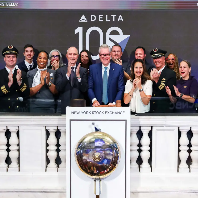 Ed standing in front of the NYSE bell with a group of employees, all clapping