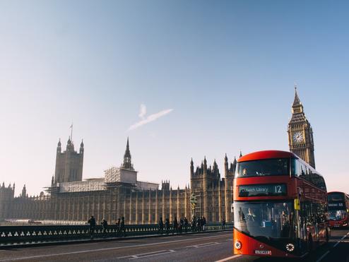 A double-decker bus rides past the Palace of Westminster in London