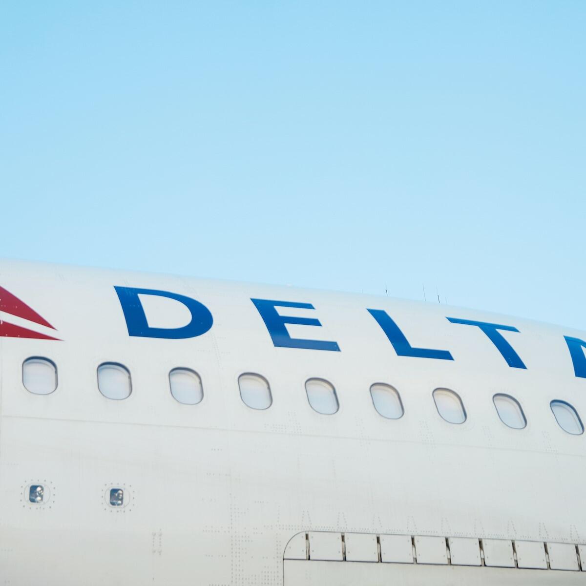 The side of a Delta aircraft against a blue sky
