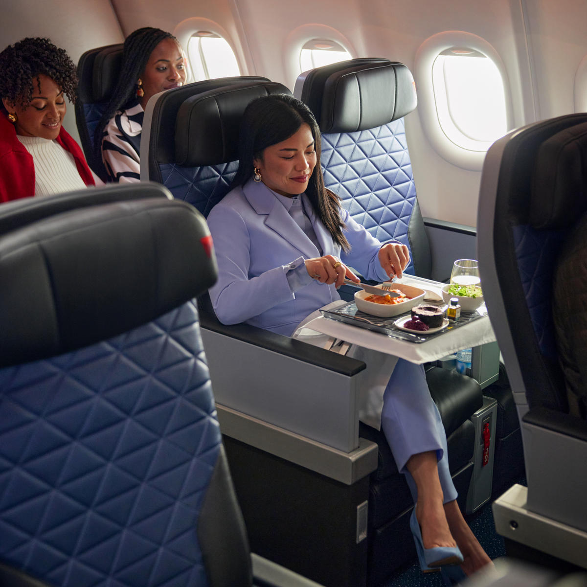A Delta customer seated in Delta Premium Select enjoys a meal.