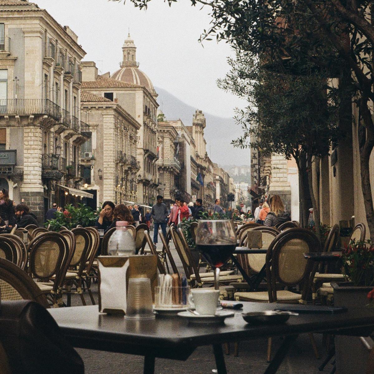 A scenic street in Catania, Sicily with cafe tables and chairs