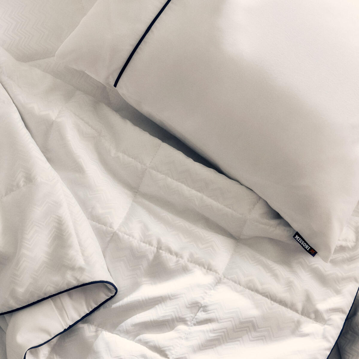 El nuevo juego de cama de Delta One incluye el edredón Missoni y una almohada blanca para dormir, con un sutil y elegante diseño en zigzag de Missoni y detalles en azul marino.