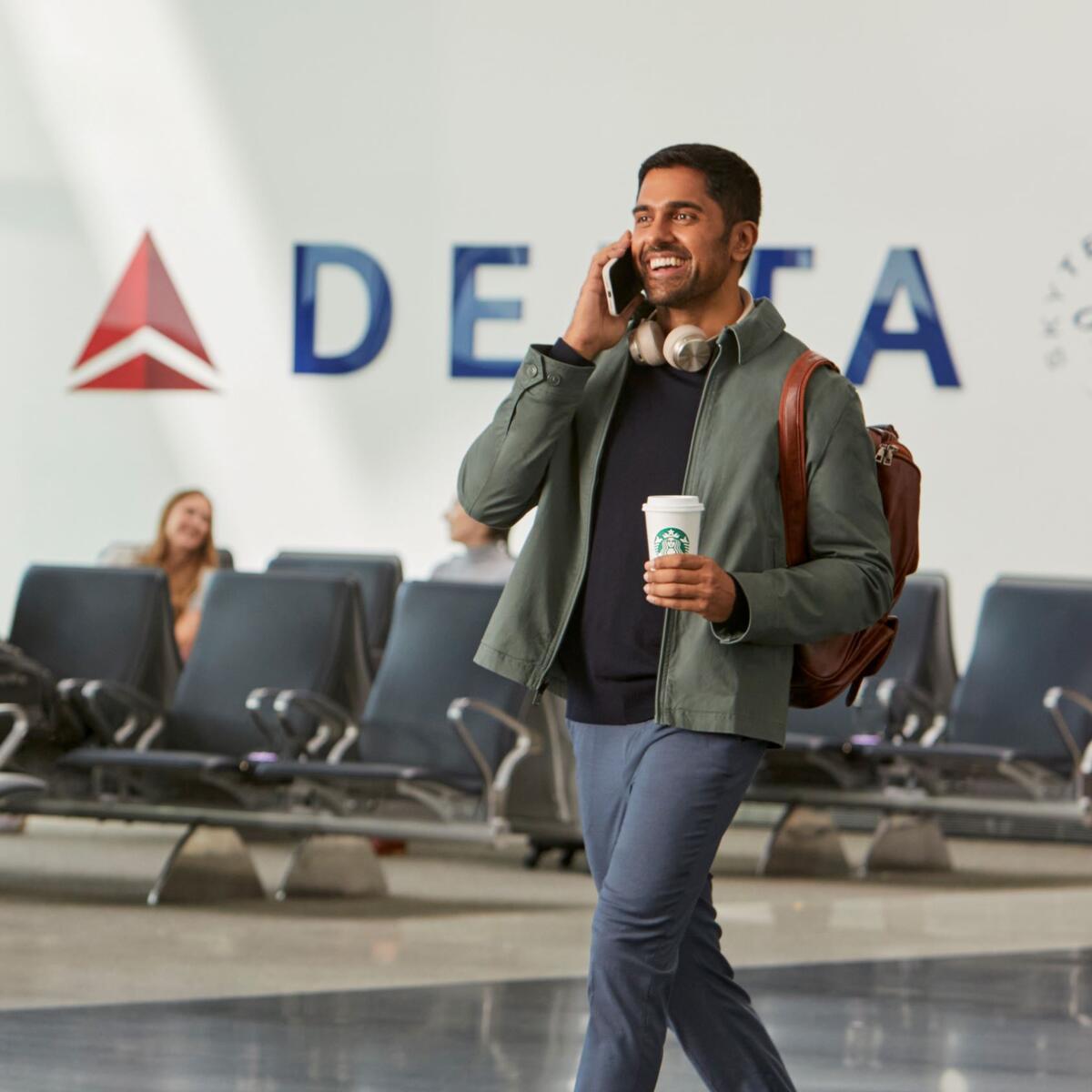 Delta customer en route through airport enjoying Starbucks beverage