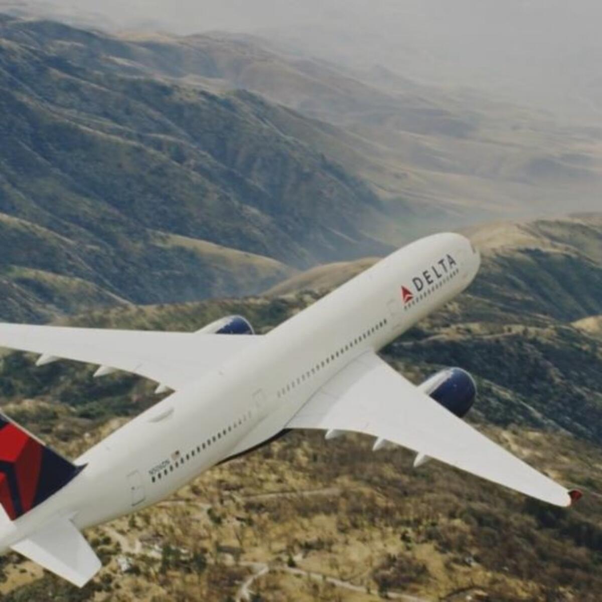 An A350 Delta aircraft flies over mountains
