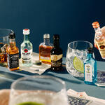A lineup of airplane bottles of alcohol against a blue background