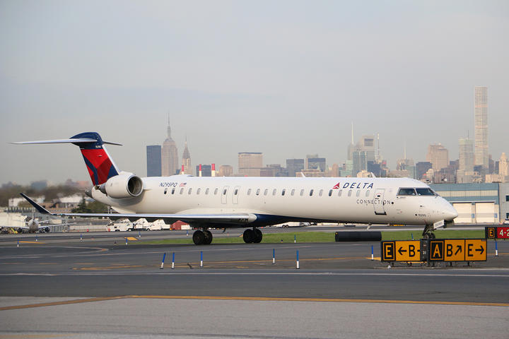 Delta's CRJ-900, one of the three aircraft in the Bombardier collection, prepares for takeoff while overlooking a bustling city skyline.