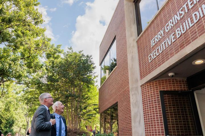 Delta CEO Ed Bastian and former Delta CEO Jerry Grinstein look up at a building.