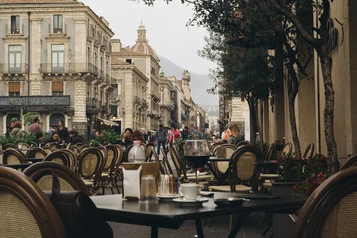A scenic street in Catania, Sicily with cafe tables and chairs