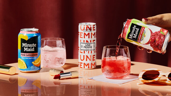 Promotional beverage display featuring Minute Maid Pink Lemonade and Cranberry Cocktail, sparkling rosé, and two iced drinks on a tabletop with lipstick and sunglasses accents.