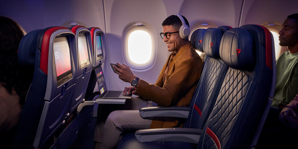 A customer uses Delta's fast, free Wi-Fi on board on their smart phone and laptop.