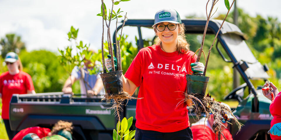 A Delta volunteer holds mangroves.