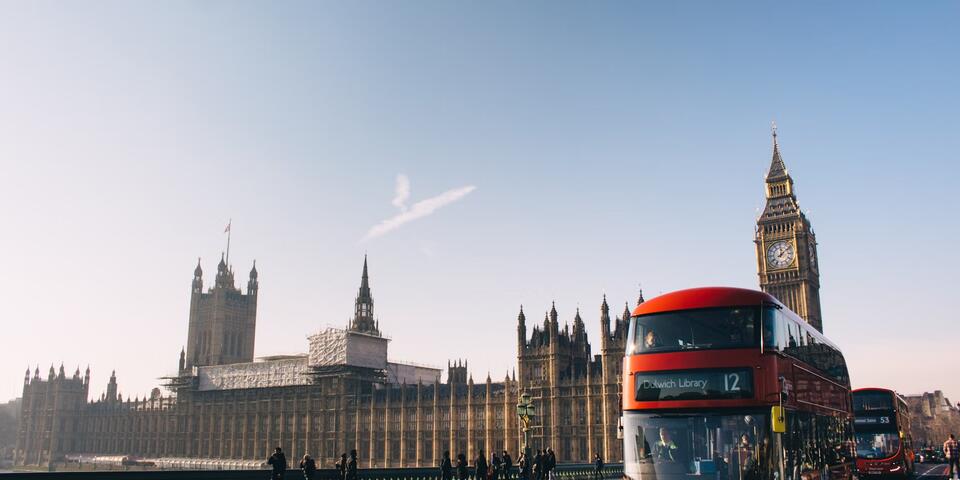 A double-decker bus rides past the Palace of Westminster in London