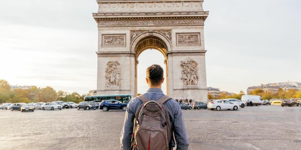 A traveler stands in front of the Arc de Triomphe in Paris, France.