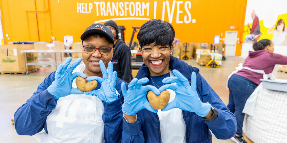 Delta employee volunteers holding heart-shaped potatoes
