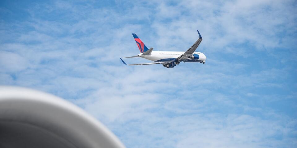Delta 767 aircraft shortly after takeoff with blue sky and clouds in background