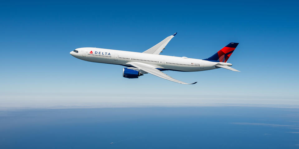 An Airbus A330-900neo in flight against a blue sky