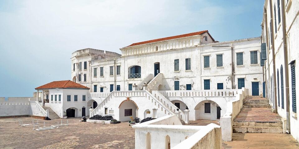 Ghana's Elmina Castle beneath a blue, lightly cloudy sky.
