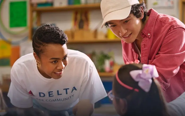 Delta employee volunteer smiling while interacting with a young girl.