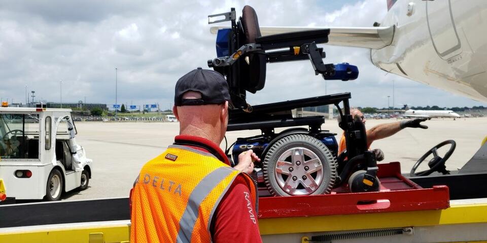 A Delta ramp agent loads a wheelchair onto a plane.
