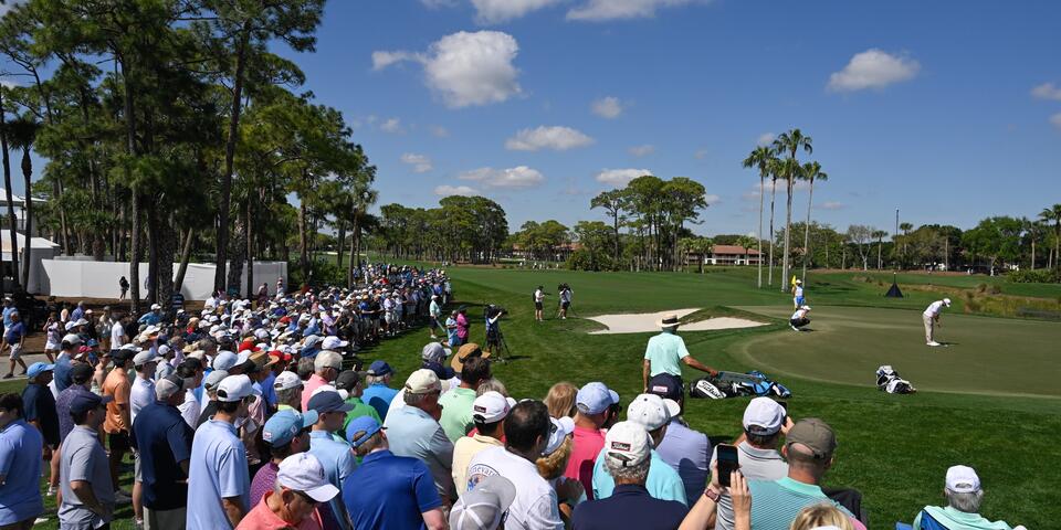 Fans surround a golf green while attending a PGA Tour event.