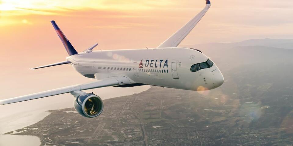Delta A350 flying above a city at sunset.