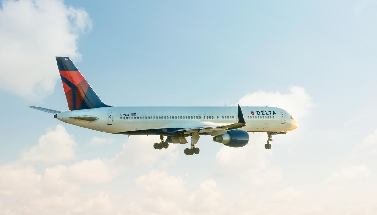 A 757-200 takes off for departure into a clouded sky.