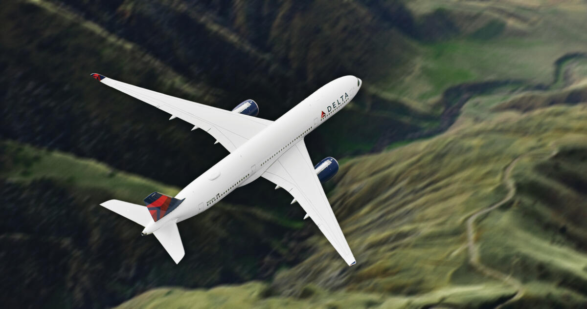 Airbus A359-900 flies over green mountains