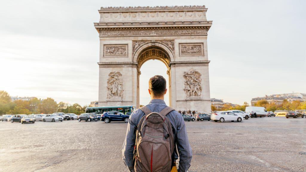 A traveler stands in front of the Arc de Triomphe in Paris, France.