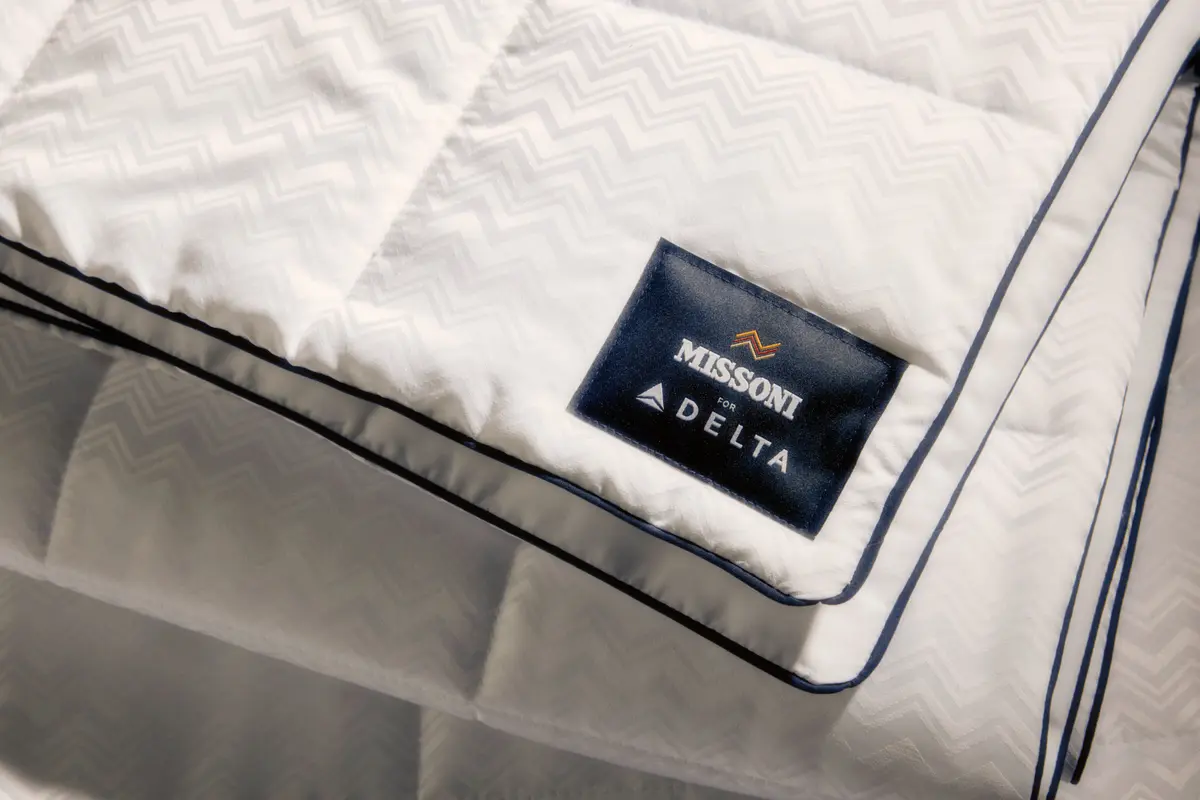 El nuevo juego de cama de Delta One incluye el edredón Missoni y una almohada blanca para dormir, con un sutil y elegante diseño en zigzag de Missoni y detalles en azul marino.
