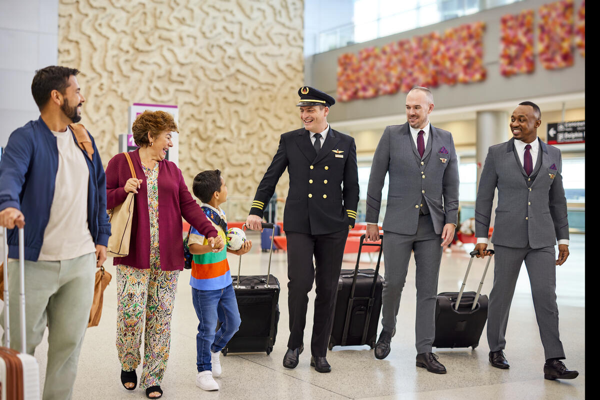 A Delta flight crew speaks with a family at an airport.
